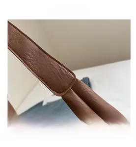 Detailed view of brown leather shoulder strap with neat stitching and litchi texture