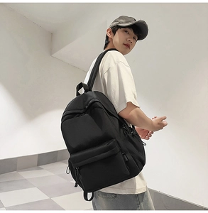 Minimalist black backpack showing side profile and adjustable straps on steps