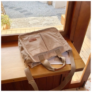 Detail view of khaki corduroy tote bag showing front pockets and fashion leather label