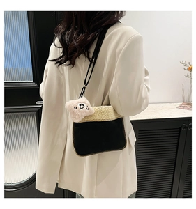 Detail of plush black and cream contrast handbag featuring cute pink monster charm accessory
