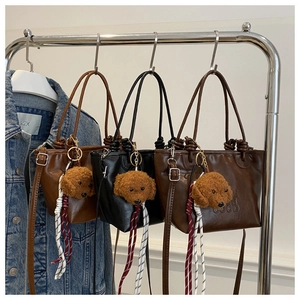 Detailed view of leather shoulder bags in brown and black with cute teddy bear charms