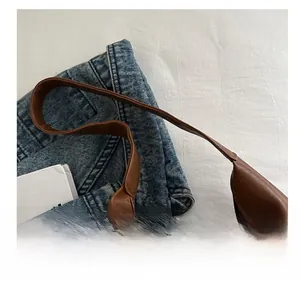 Close-up detail of soft brown leather tote bag handle showing high-quality texture
