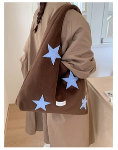 Detail view of large brown plush tote bag featuring blue star embroidery and side label