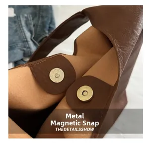 Macro shot of the bright gold magnetic metal clasp on the vintage brown tote bag