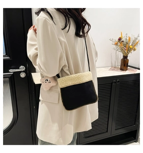 Detail view of mini plush crossbody bag in black and cream worn over white blazer