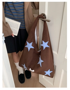 Brown faux suede tote bag with blue star embroidery detail hanging on a door handle
