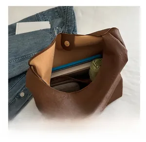 Detail view of large brown tote bag showing spacious interior with books and umbrella
