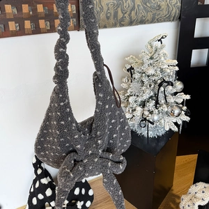 Detail of grey plush faux fur shoulder bag with white polka dots and oversized bow