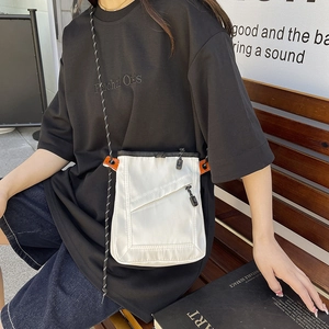 White nylon square crossbody bag with orange accents and woven rope strap on a model