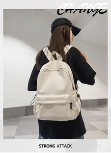 Detail view of the cream white canvas backpack with large front zip pocket and side drawstrings