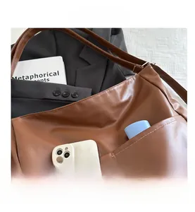 Detail view of brown leather tote bag exterior pocket holding a mobile phone