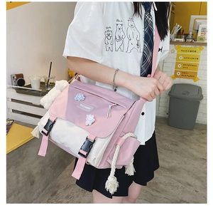 Detail of pink and beige canvas messenger bag with plastic buckle and cartoon badge