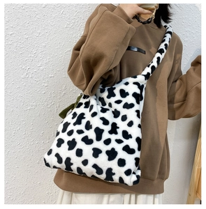 Detail view of cow pattern plush crossbody bag showing soft texture and wide strap