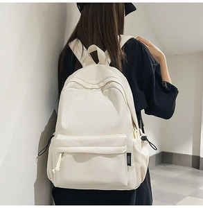 Detail view of cream minimalist backpack showing nylon texture and side drawstring pockets