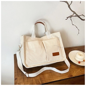 Close-up of beige corduroy tote bag with dual pockets and adjustable fabric shoulder strap