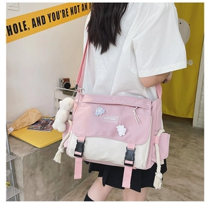 Detail of pink and beige messenger bag featuring twin buckles and cotton rope tassels