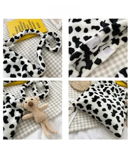 Detail view of cow print plush bag with velcro closure and a teddy bear pendant