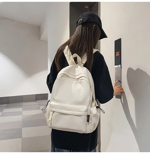 Rear view of a cream-white minimalist nylon backpack worn in a casual lifestyle setting