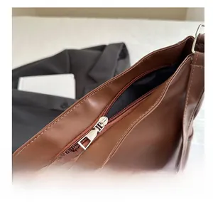 Detailed macro view of the smooth silver zipper closure on a brown leather tote bag