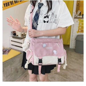 Detailed view of pink and white canvas messenger bag with adjustable strap and bear charm