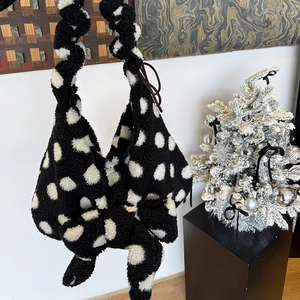 Close-up of black and white polka dot plush tote bag with a decorative bow knot