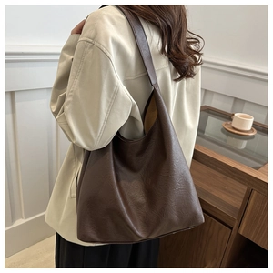 Detail of soft leather texture on a dark brown large-capacity tote bag with shoulder strap