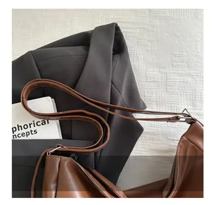 Detail of soft brown faux leather tote with adjustable strap and silver metal buckle