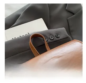 Detail view of the brown leather backpack handle with durable reinforced stitching
