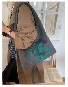 Detail of grey felt tote bag featuring green Day Dreaming Club embroidery on the front