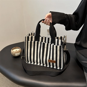Vertical black and white striped canvas tote bag with black handles and shoulder strap