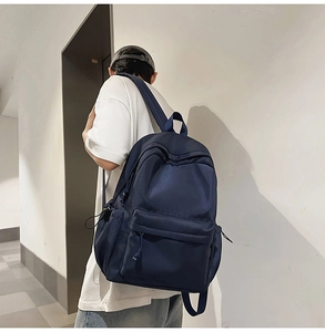 Rear view of model wearing a navy blue minimalist backpack with adjustable side cords