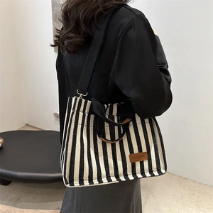 Vertical striped canvas tote bag with black shoulder straps and leather trim detail