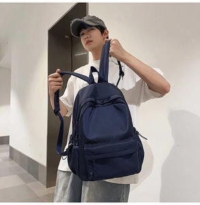 Detailed view of a dark blue large capacity nylon backpack on a male model's shoulder