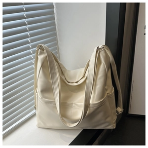 Close-up of cream large tote bag with side pockets and fine stitching details