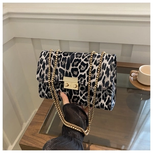 Detail of leopard print handbag with golden square lock and elegant chain straps
