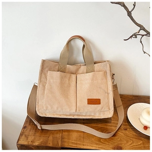 Detailed close-up of corduroy tote bag with dual front pockets and adjustable strap