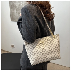 Detail der bedruckten Shopper-Tasche mit M-Logo, Kettenriemen und Reh-Anhänger-Dekor