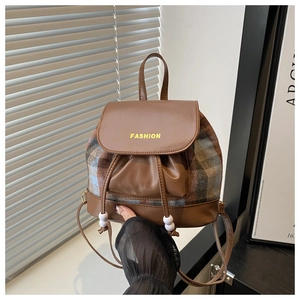 Detail of vintage plaid tweed backpack with brown leather trim and fashion text logo