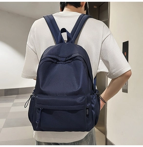 Rear view of a navy blue minimalist backpack with multiple pockets on a person