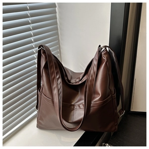 Detail view of the deep brown PU leather tote bag with subtle natural window lighting