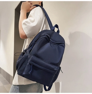 Detail view of the deep blue minimalist backpack with waterproof fabric on a model
