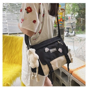 Detail of crossbody canvas bag with cartoon badges and white plush bear pendant