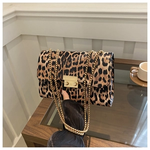 Close-up of leopard print shoulder bag featuring gold chain strap and metal buckle closure