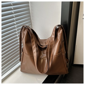 Detail view of brown large PU leather tote bag with side pockets and smooth texture