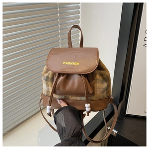 Detailed view of vintage plaid pattern and PU leather trim on small bucket backpack