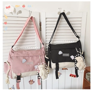 Detail of canvas messenger bag with dual buckles and cute plush bear charm decoration