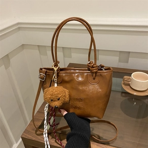Brown vintage faux leather tote bag with embossed text and plush dog keychain