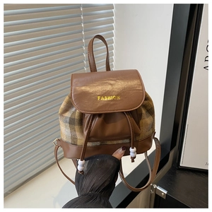 Detail of vintage plaid fabric and brown leather backpack with gold Fashion lettering