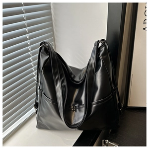 Detail of black PU leather tote bag with side pockets and elegant window light shadows