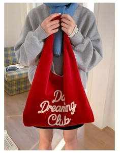 Detail of red plush tote bag featuring white embroidered 'Day Dreaming Club' text